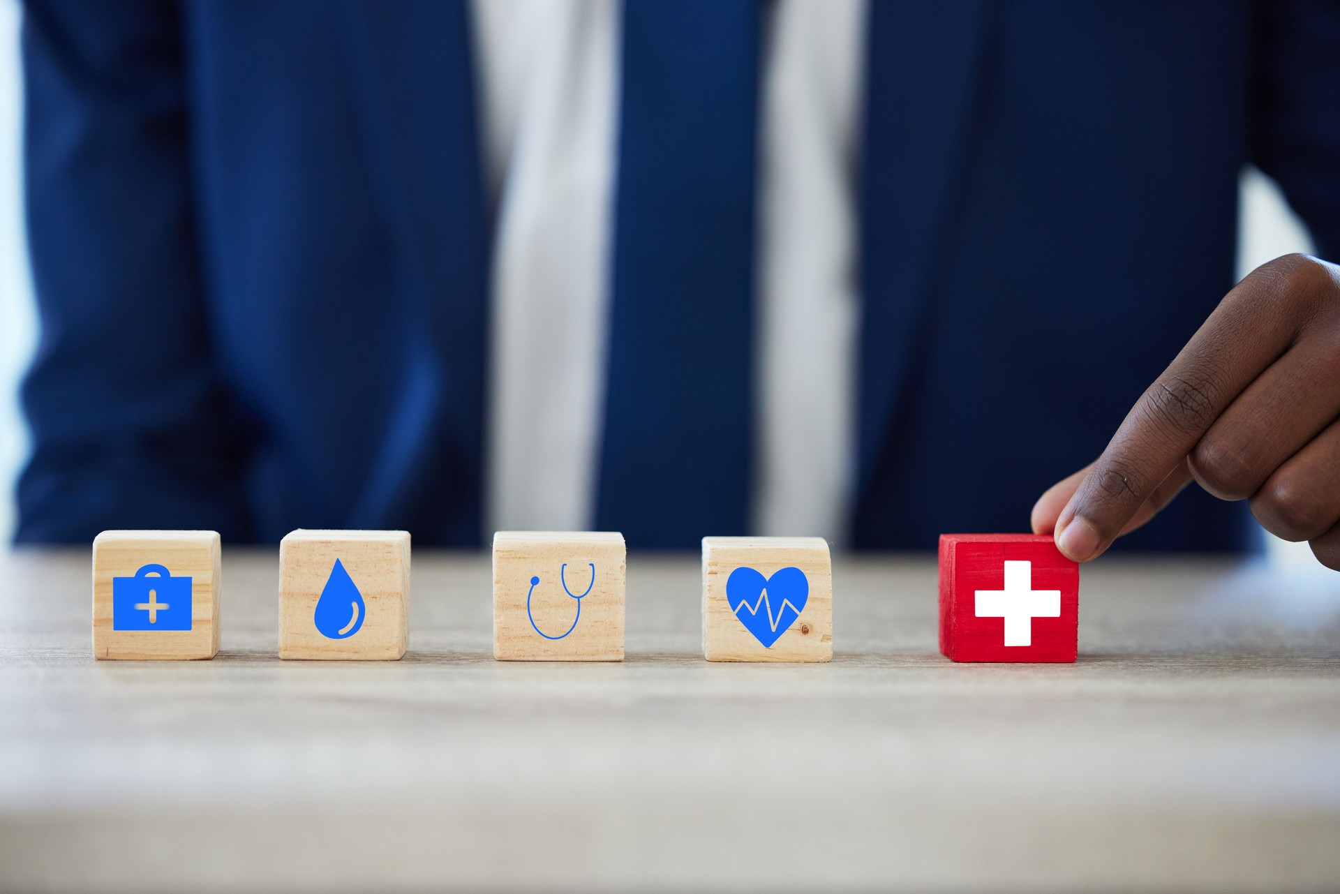 Shot of an unrecognisable businessman assembling building blocks with medical icons on them. Insurance Underwriting Support